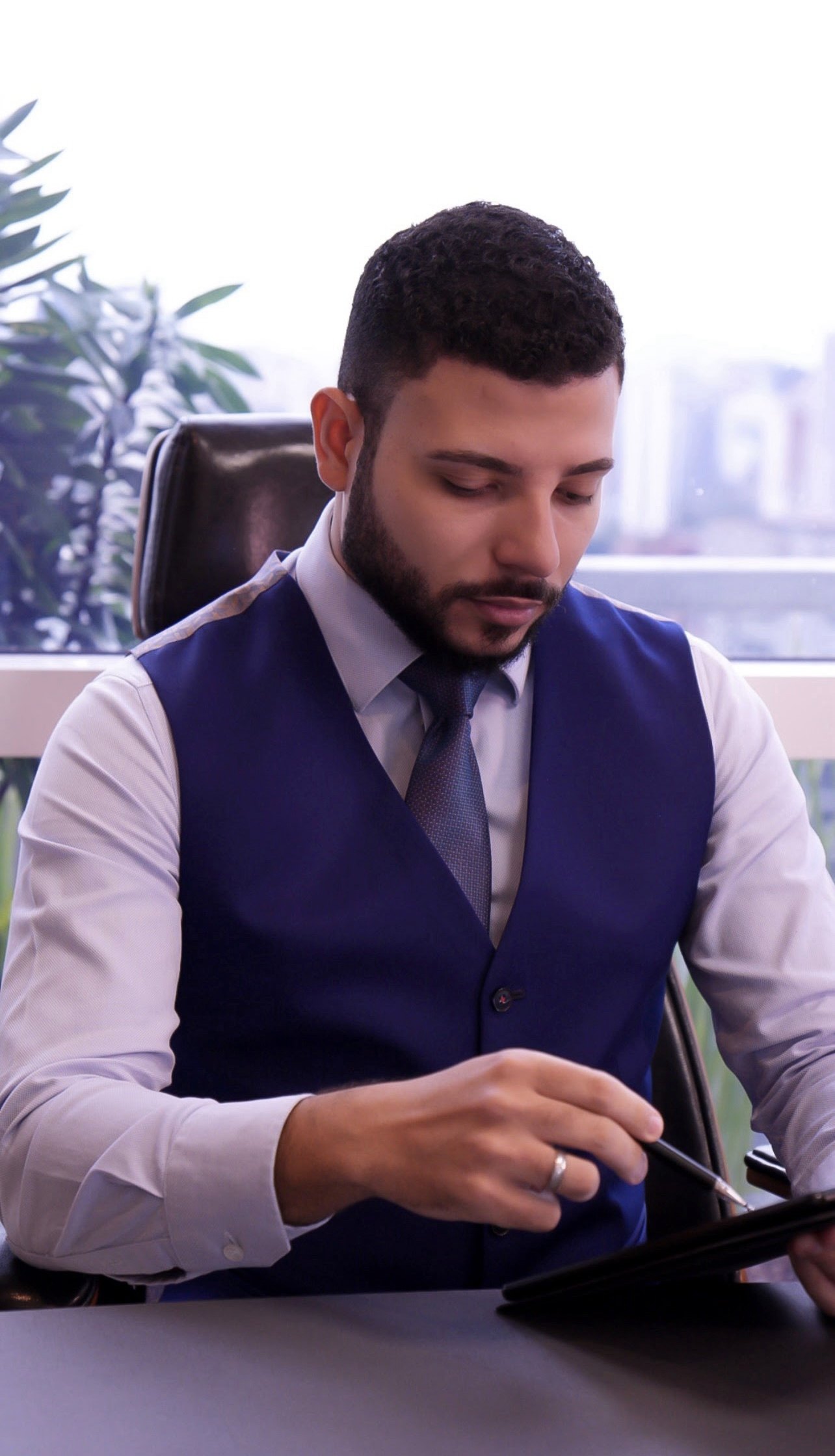 Dr. Mateus Bonutty à mesa do consultório, com vista para a cidade